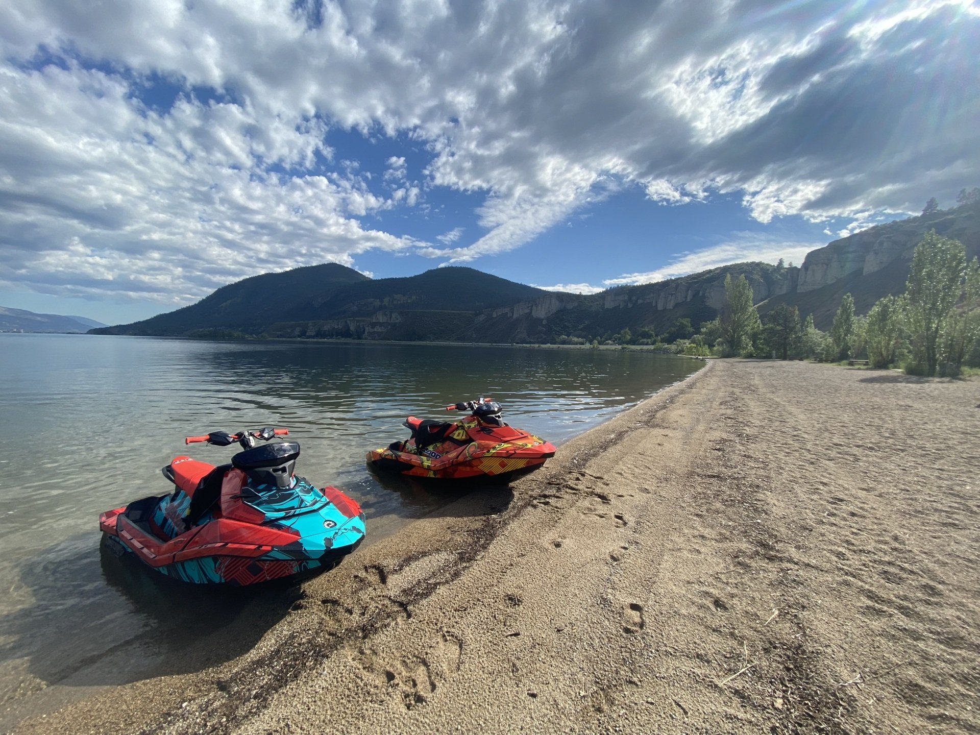 Two Sea-Doos pulled up on a sandy beach below the cliffs